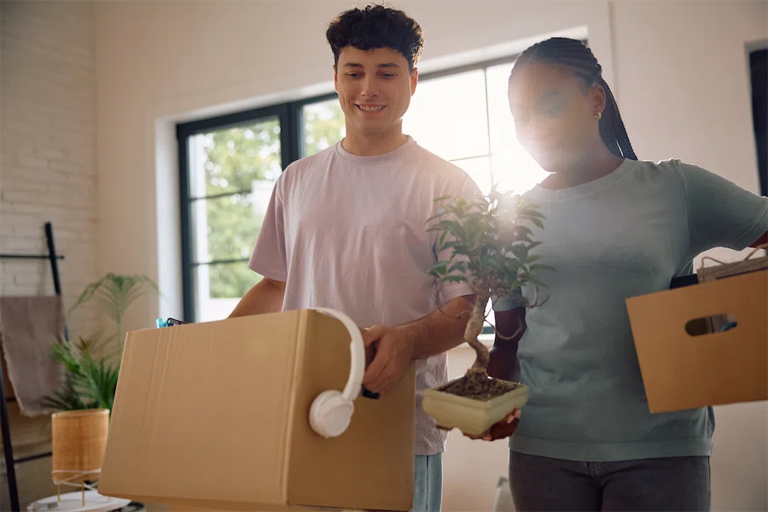 A happy couple carrying boxes and belongings into their new home, representing active homebuyers.